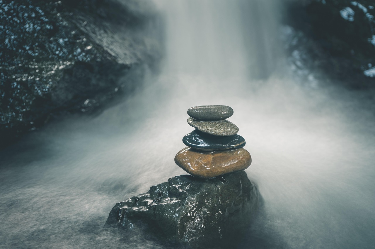 Stones on a rock, with a waterfall flowing in the background